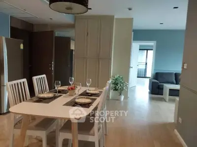 Modern dining area with elegant table setting and cozy living room in open layout apartment.