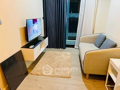 Cozy living room with modern decor and balcony access, featuring a comfortable sofa and mounted TV.