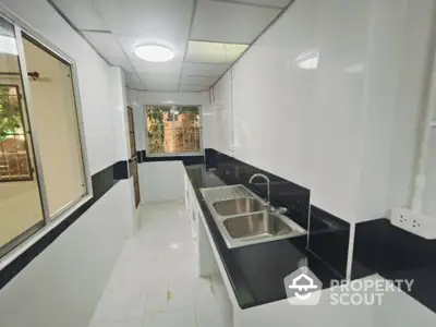 Modern kitchen with sleek black and white design, featuring double sink and ample counter space.