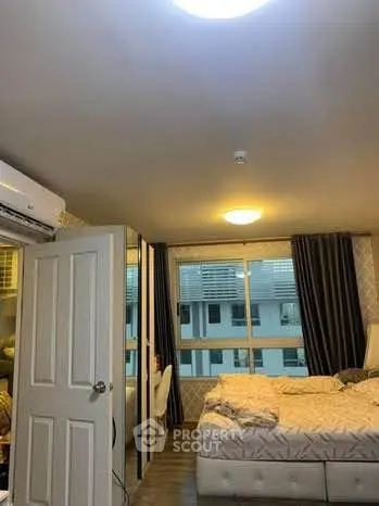 Cozy bedroom with modern decor and large window offering natural light.