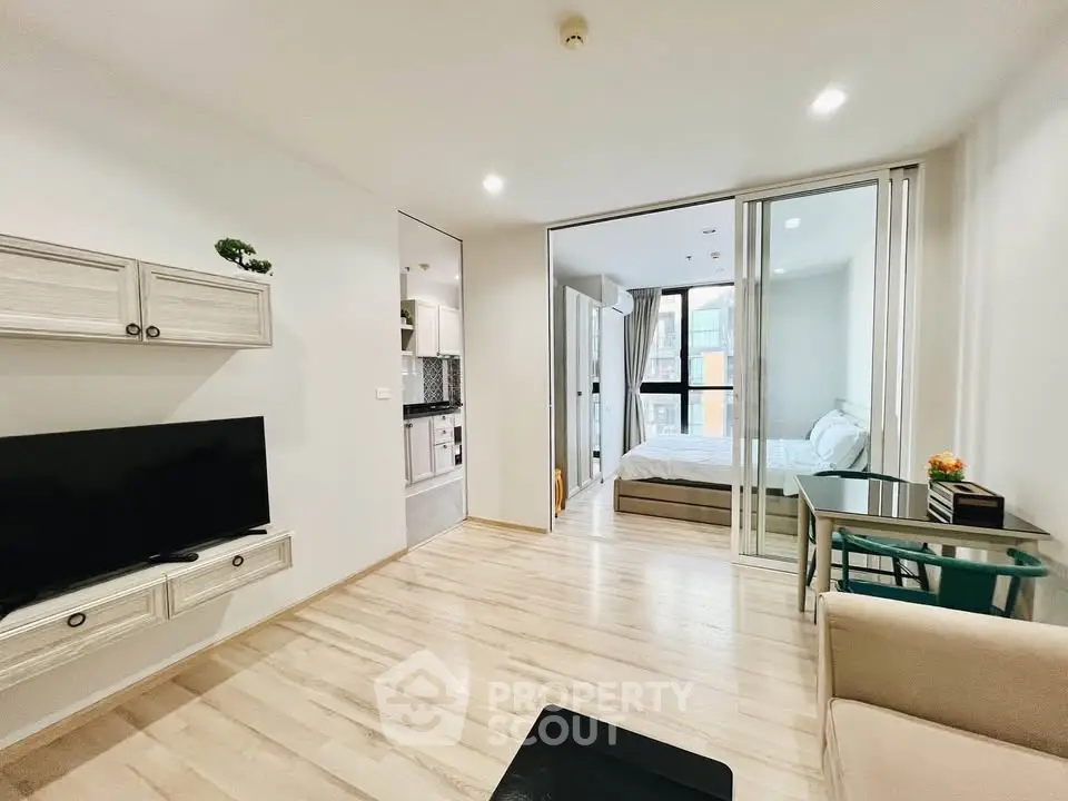 Modern open-plan living room with sleek design and natural light, featuring a cozy bedroom view.