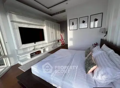 Luxurious bedroom with modern decor and large TV, featuring elegant wall art and plush bedding.