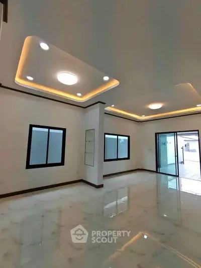 Spacious modern living room with elegant ceiling lights and large windows, perfect for natural light.