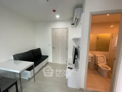 Modern compact living room with adjacent bathroom, featuring sleek furniture and minimalist design.