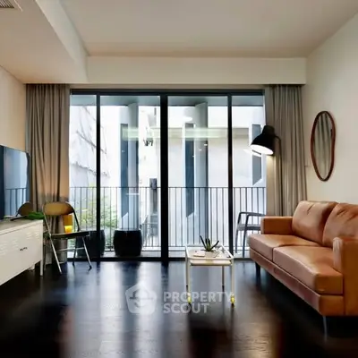 Modern living room with sleek design and large windows opening to a balcony, featuring a leather sofa and stylish decor.