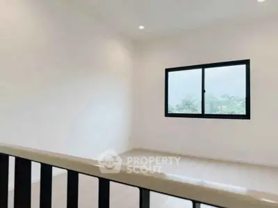 Bright and airy room with large window and modern railing, perfect for a cozy living space.