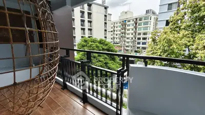 Spacious balcony with city view and hanging chair, perfect for relaxation.