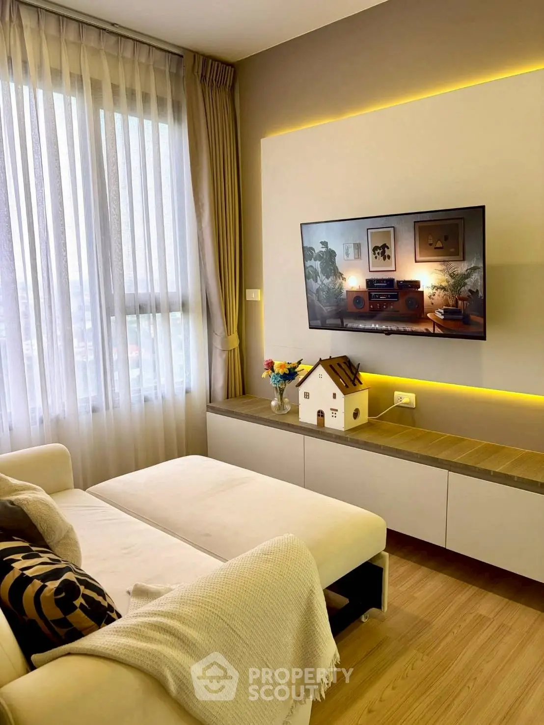 Modern living room with cozy sofa and wall-mounted TV, featuring elegant decor and natural light.