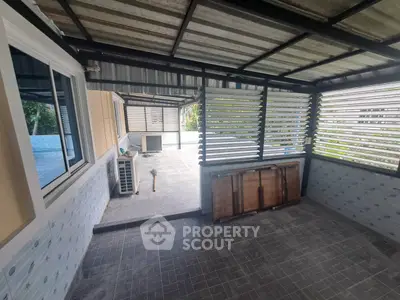 Spacious covered patio with tiled flooring and louvered walls, ideal for outdoor relaxation.