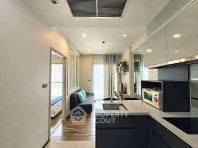 Modern open-layout kitchen with sleek cabinetry and cozy living area in a stylish apartment.