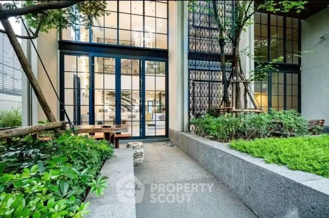 Modern building entrance with lush greenery and large glass windows