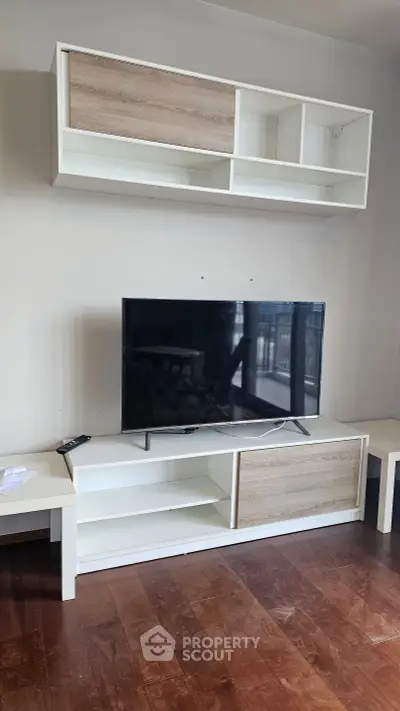 Modern living room with sleek TV stand and mounted shelves, featuring hardwood floors.