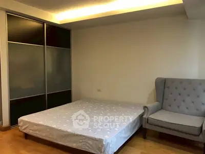 Spacious bedroom with modern sliding wardrobe and cozy armchair