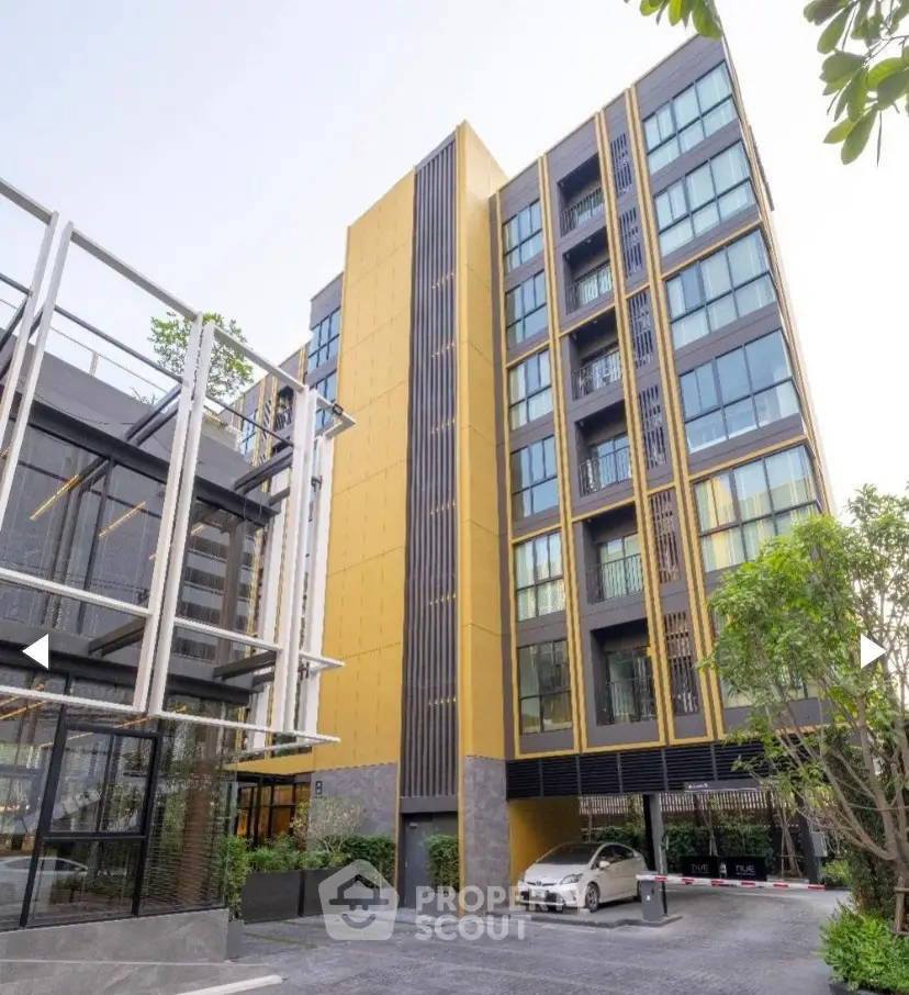 Modern apartment building with sleek design and ample parking space.