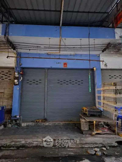 Commercial property with closed shutters in urban setting, ideal for small business or storage use.