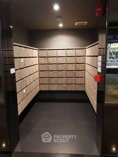 Modern apartment building mailroom with sleek wooden mailboxes and dark flooring.