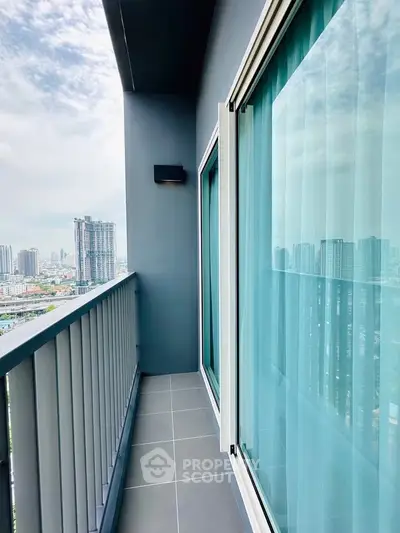 Modern high-rise balcony with city skyline view and sleek glass doors.