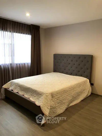 Spacious bedroom with elegant bed and natural light from large window