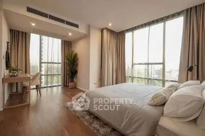 Spacious bedroom with large windows and modern decor, perfect for relaxation.