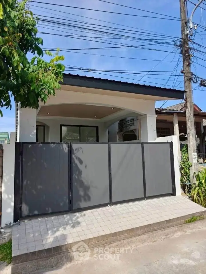 Modern single-story home with sleek design and gated entrance in a suburban neighborhood.