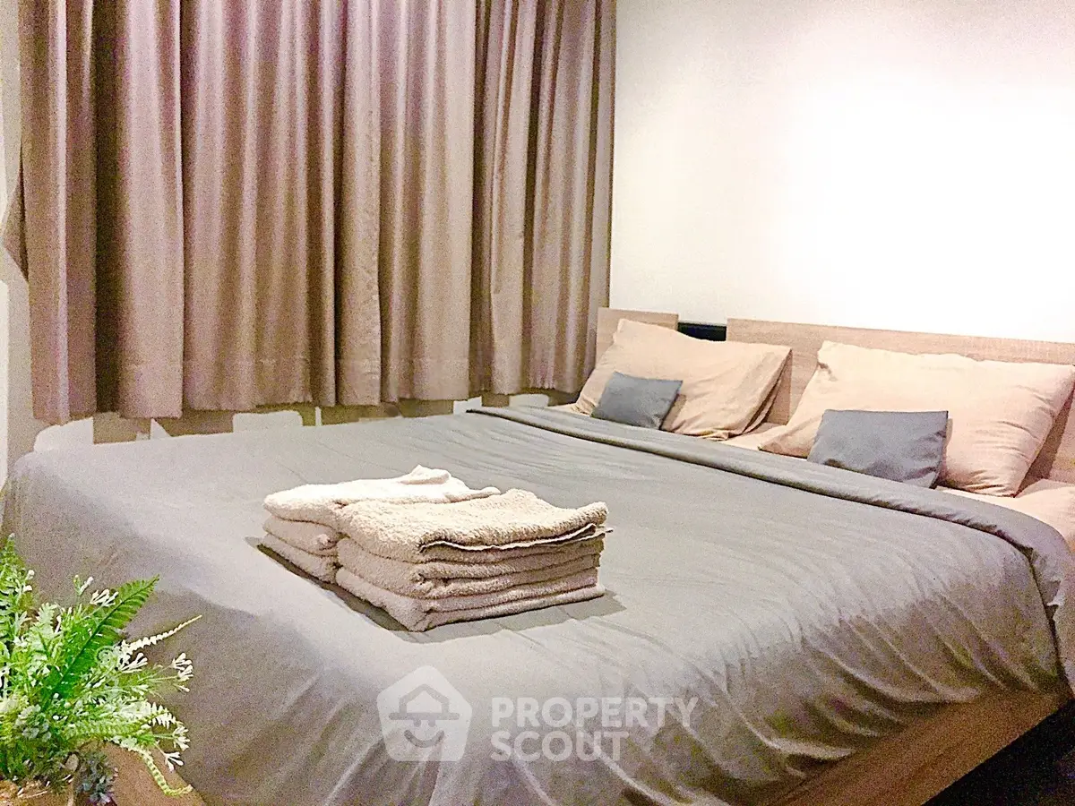 Cozy bedroom with neatly arranged bed and soft lighting, perfect for relaxation.