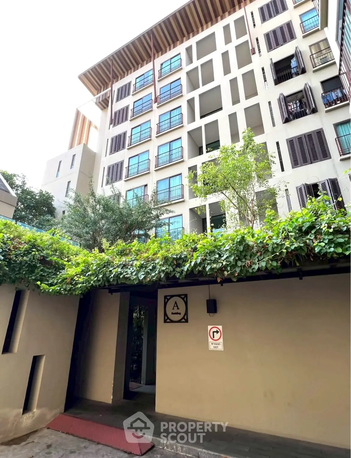 Modern apartment building exterior with lush greenery and unique architectural design.