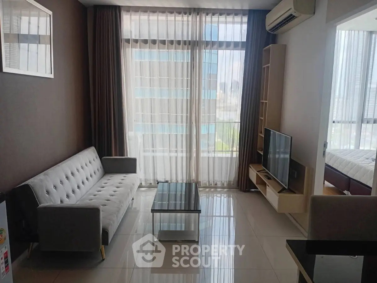 Modern living room with sleek furniture and large windows offering natural light in a stylish apartment.