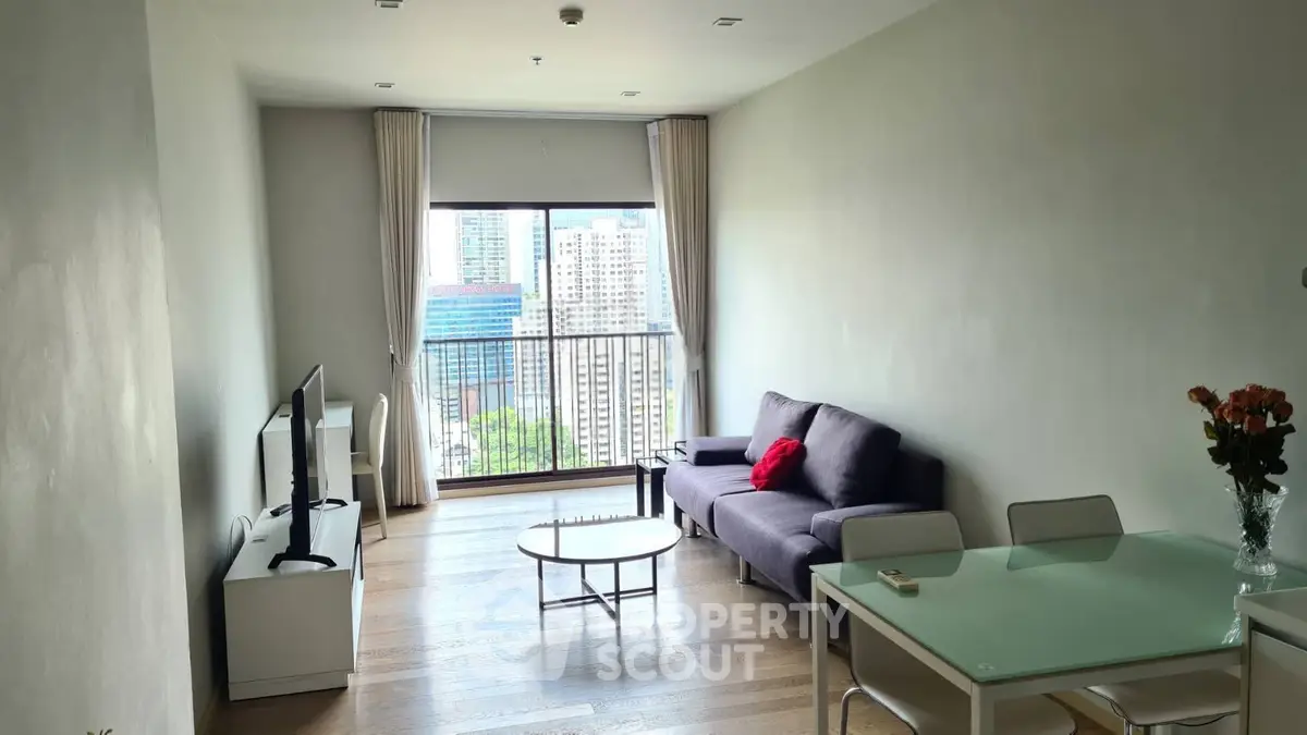 Modern living room with city view, featuring a cozy sofa, TV, and dining area in a high-rise apartment.