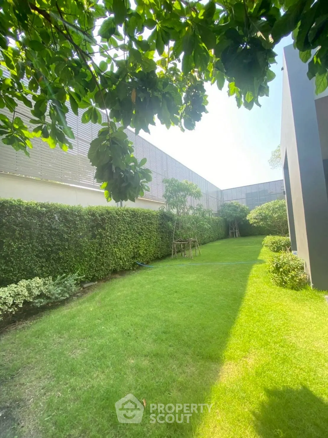 Lush green garden with manicured lawn and modern building facade, perfect for relaxation and outdoor activities.