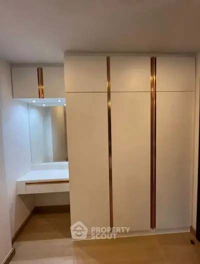 Modern bedroom with built-in wardrobe and vanity mirror, featuring sleek design and ample storage space.