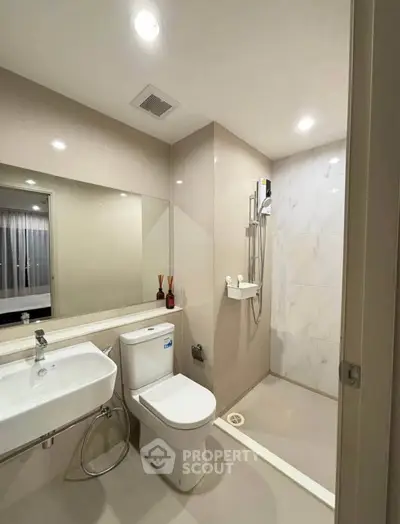 Modern bathroom with sleek fixtures and spacious shower area in a contemporary apartment.