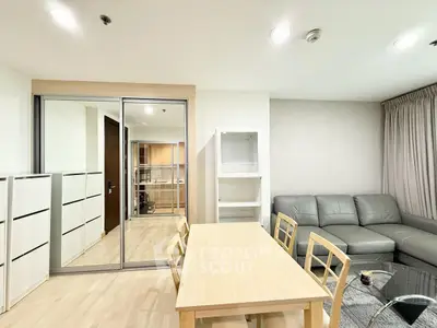 Modern living room with sleek furniture and dining area, featuring a cozy gray sofa and wooden table.