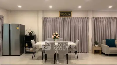 Modern dining area with elegant table and chairs, adjacent to a cozy living space and sleek refrigerator.