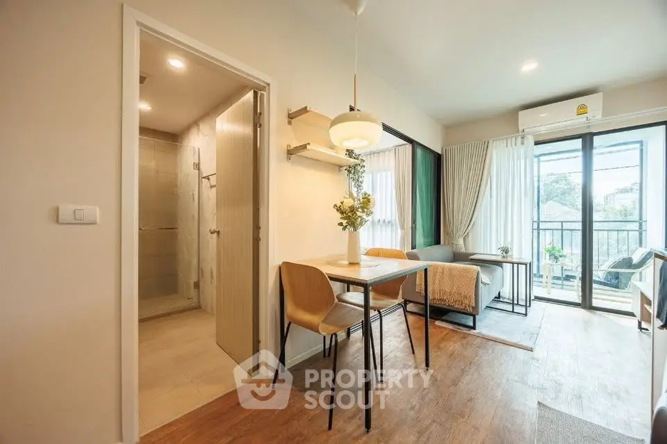 Modern open-plan living room with dining area and balcony access, featuring stylish decor and natural light.