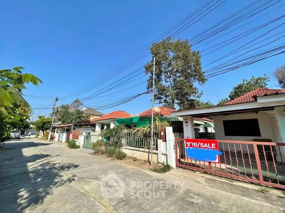Charming suburban house for sale with red roof and gated entrance in a peaceful neighborhood.