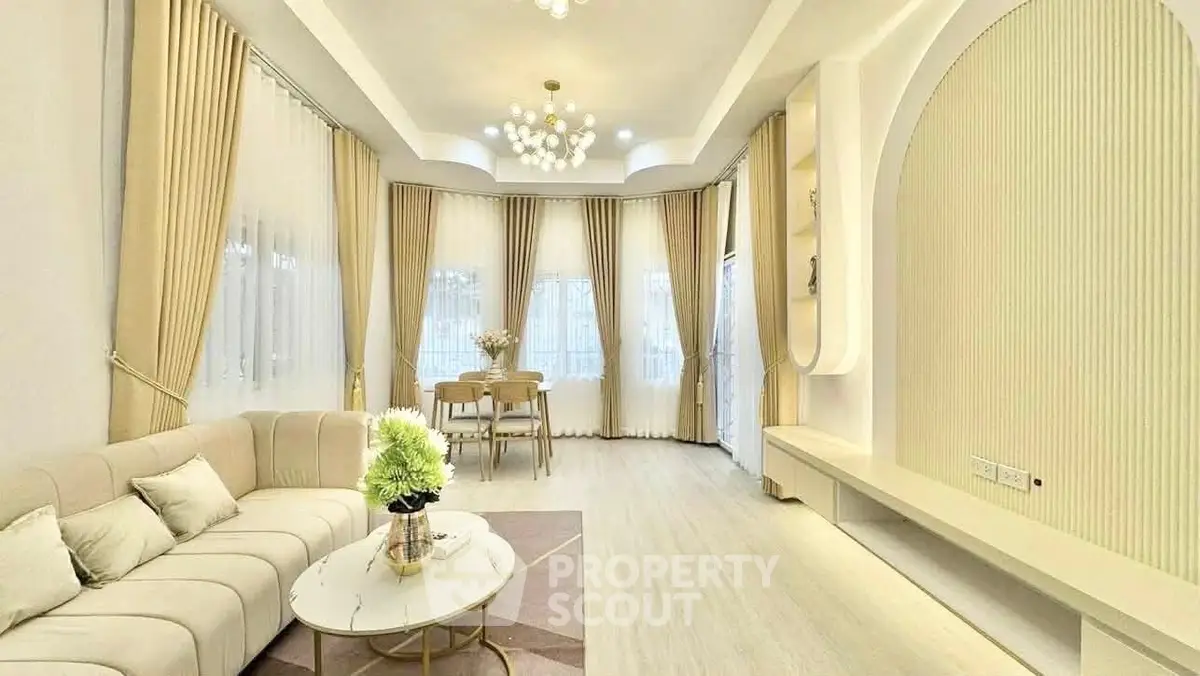 Elegant living room with modern decor and large windows, featuring a cozy seating area and stylish lighting.