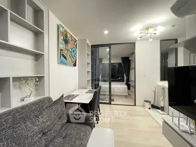 Modern open-plan living room with stylish decor and glass partition to bedroom