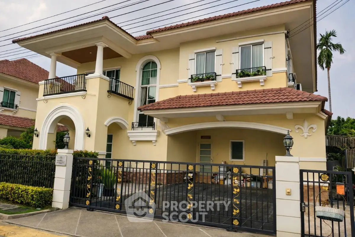 Elegant two-story house with balcony and gated driveway in a serene neighborhood.