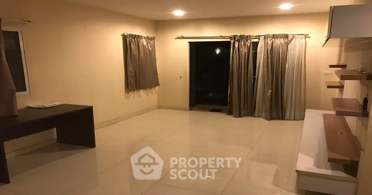 Spacious unfurnished living room with tiled flooring and large windows.