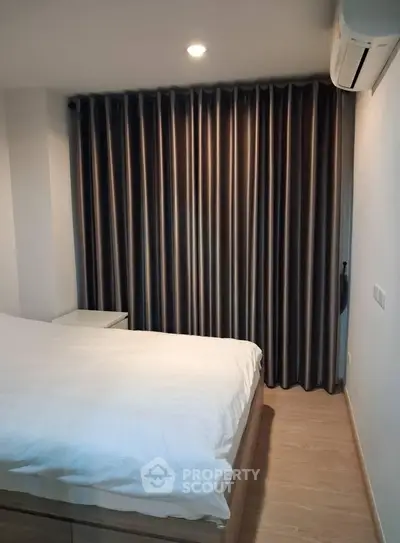 Cozy bedroom with modern curtains and air conditioning, perfect for a comfortable living experience.