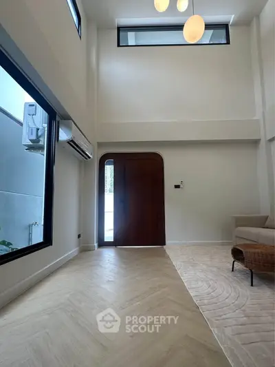 Spacious modern living room with high ceilings and large windows, featuring elegant lighting and stylish flooring.