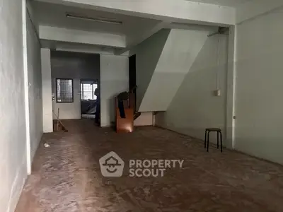 Spacious empty room with concrete floor and staircase, ideal for renovation or storage.