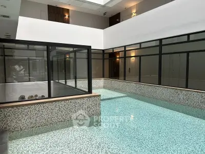 Luxurious indoor pool with modern glass enclosure and elegant mosaic tiles