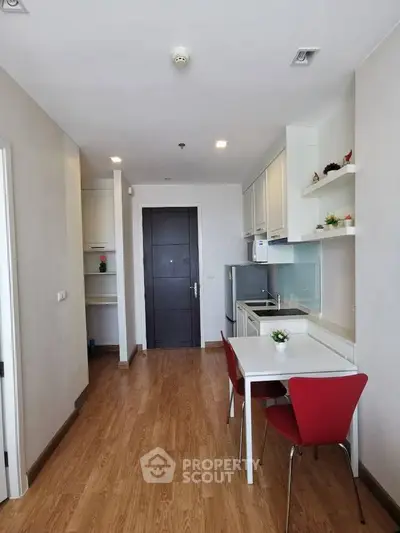 Modern apartment interior with open kitchen and dining area featuring sleek design and wooden flooring.