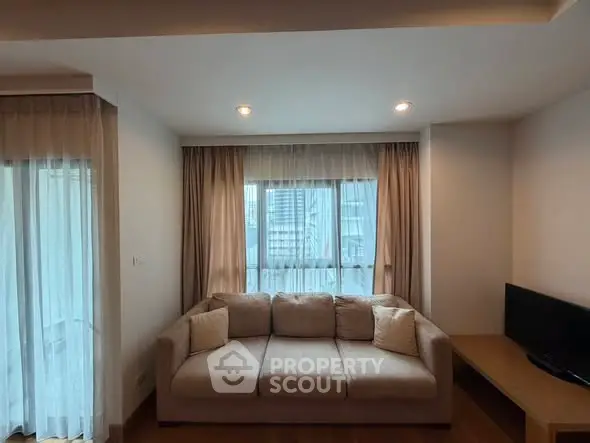 Cozy living room with a plush sofa and city view through large windows.