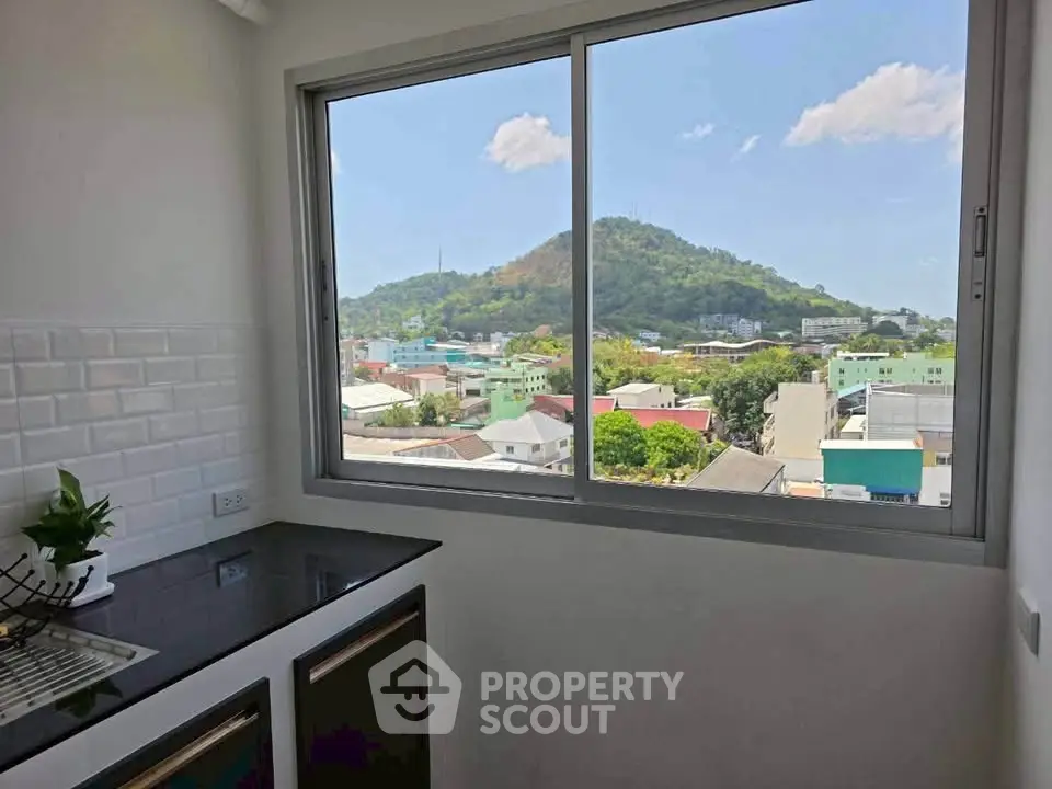 Modern kitchen with stunning mountain view through large window, featuring sleek countertops and stylish backsplash.