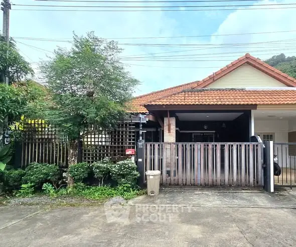 Charming single-story home with a red-tiled roof and lush greenery, perfect for serene living.