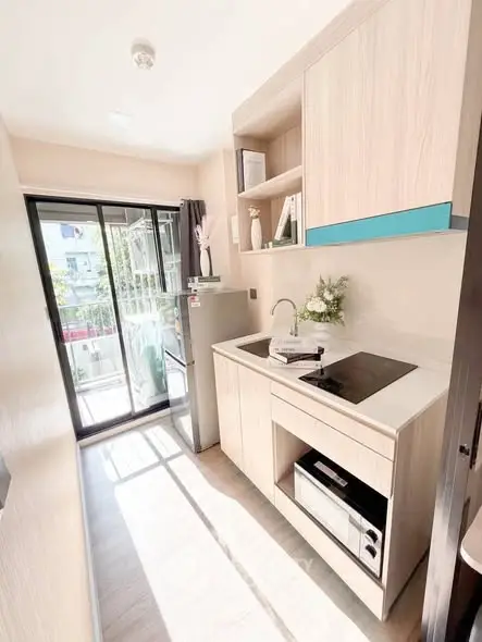 Modern compact kitchen with natural light and sleek appliances in a stylish apartment.