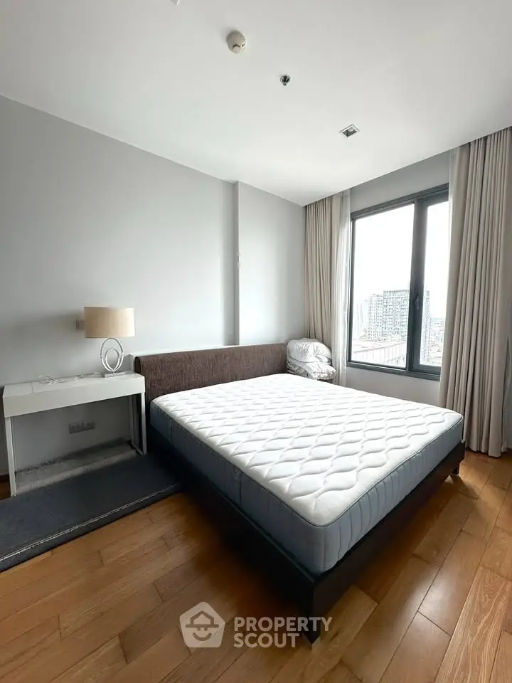 Modern bedroom with large window and sleek furnishings in urban apartment