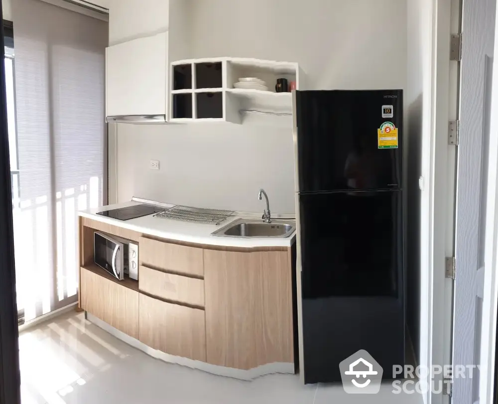 Modern compact kitchen with sleek black fridge and built-in microwave